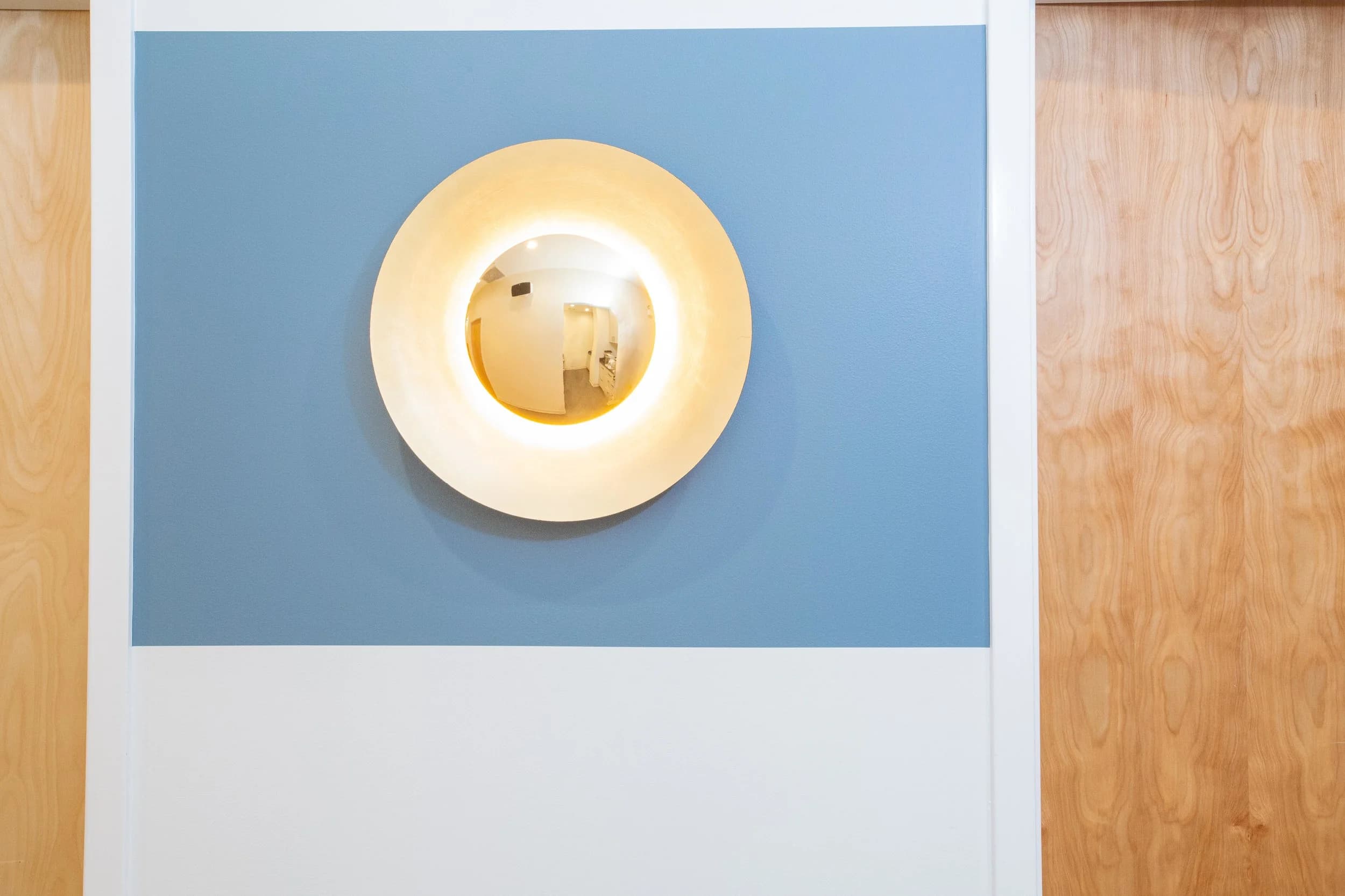 A wall sconce on the blue panel by the wood-clad wall